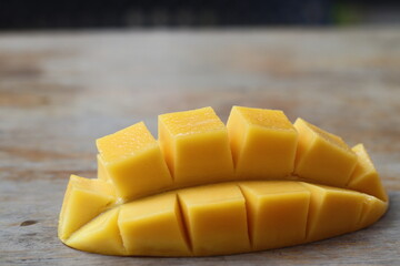 Half of ripe yellow mango fruit on wood background