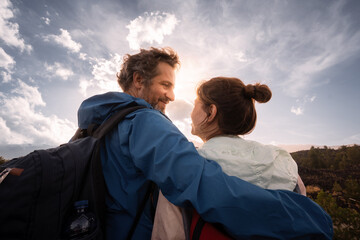 Romantic hiking couple, surrounded by the vastness of nature, shares an intimate moment against...
