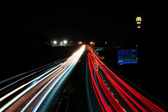 Light trails on the highway at night and McDonalds logo with McCafe sign. Roadside service