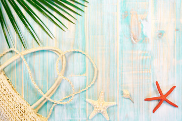Fototapeta na wymiar Summer beach vacation concept with top view composition made with beach bag, starfish, conch shell and palm leaf on worn blue wooden background