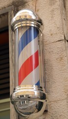 Barber shop s rotating striped pole sign with spiral design outside the business