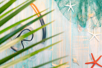Out of focus closeup of palm leaf with starfish on fishing net and diving goggles and snorkel tube...