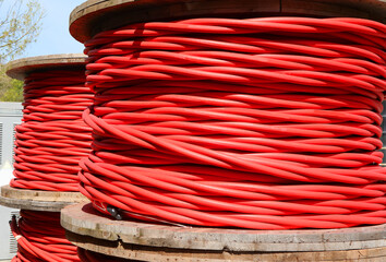 High-voltage red electrical cable reels that can carry up to 30000 volts to connect electrical...