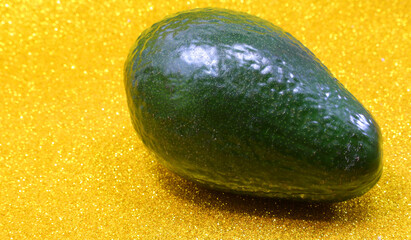 Ripe Green Avocado on golden glittery background