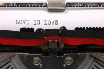 LOVE IS LOVE handwritten in black ink on white paper with an antique typewriter symbolizing...