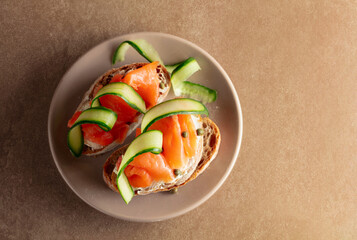 Sandwiches with smoked trout, cream cheese, fresh cucumber and capers on a stone background - 783597030