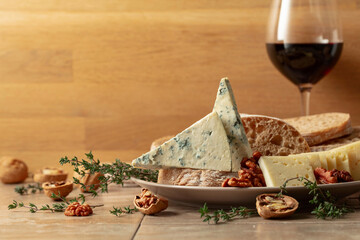 Cheese, bread, red wine, and walnuts on a kitchen table. - 783597049
