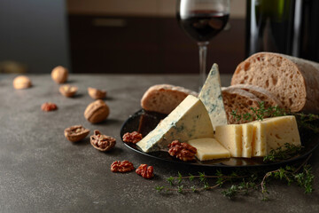 Cheese, bread, red wine, and walnuts on a kitchen table.