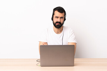 Telemarketer caucasian man working with a headset and with laptop with unhappy expression.