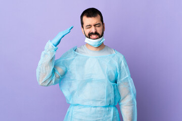 Surgeon man with beard with blue uniform over isolated purple background with tired and sick expression