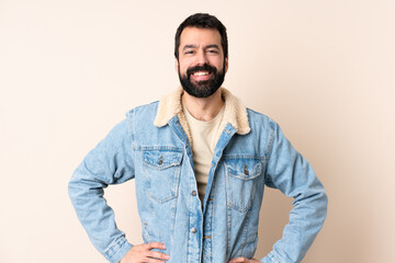 Caucasian man with beard over isolated background posing with arms at hip and smiling