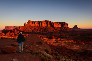 The male tourist is admiring the sunrise in Monument Valley.