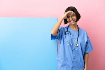 Young mixed race surgeon woman with a big banner over isolated background saluting with hand with...