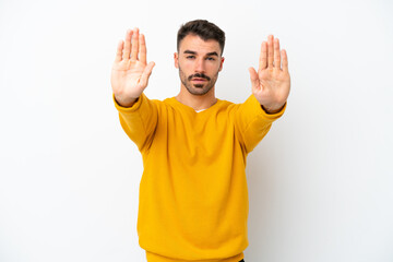 Naklejka premium Young caucasian man isolated on white background making stop gesture and disappointed