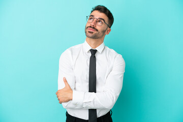 Business caucasian man isolated on blue background looking up while smiling