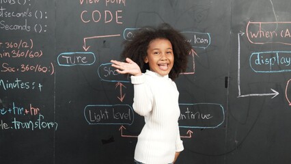 Happy african girl writing blackboard and turnaround to waving at camera while standing at board...