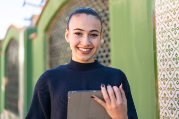 Young moroccan girl  at outdoors holding a tablet with happy expression