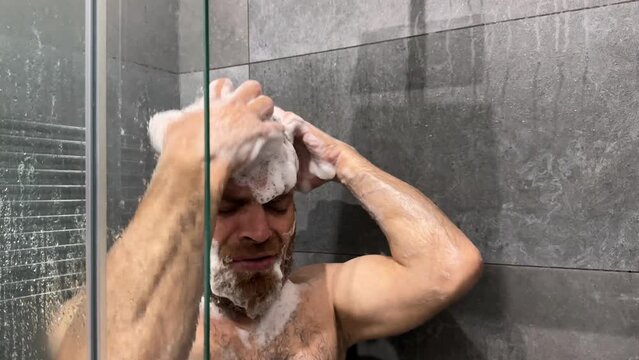 Man washes his head with shampoo in the shower