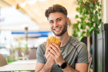 Young handsome man taking fried chips with happy expression