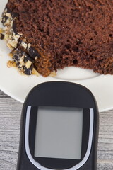 Glucose meter and sweet chocolate cake. Checking sugar level during diabetes