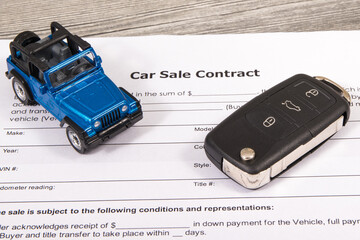Car sale contract, blue toy car and black key. Sales, purchases of vehicle