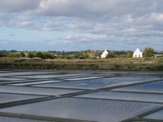 Sea water salt pans, near city le Croisic, France,  are used for the old artisan salt production in a traditional way, Houses in the background, view to the andscape 