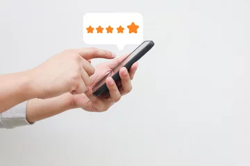 Keuken foto achterwand close up on customer man hand pressing on smartphone screen with gold five star rating feedback icon and press level three rank (good) for give score point to review the service business concept © chinnarach