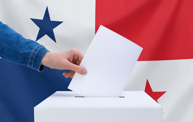 Elections, Panama. A hand throws a ballot into the ballot box. The flag of Panama on the background. The concept of voting.