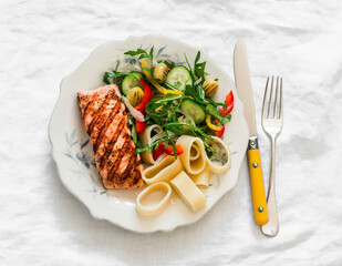 Balanced lunch - grilled salmon, pasta and fresh vegetable salad on a light background, top view - 783614285