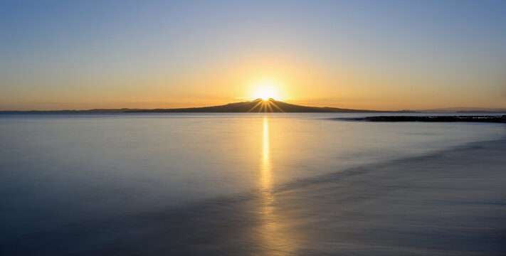 Long exposure image of sunrise over the top of Rangitoto Island. Milford Beach. Auckland.
