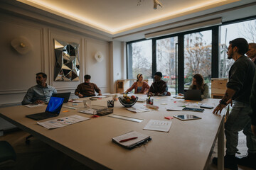 A team of diverse professionals collaborates in a well-lit office environment, discussing ideas around a conference table with laptops and notes.