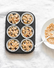 Making muffins with black currant and sugar oatmeal crumble on a light background, top view