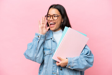 Young student Colombian woman isolated on pink background shouting with mouth wide open to the side