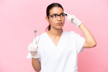 Dentist Colombian woman isolated on pink background having doubts and thinking - obrazy, fototapety, plakaty