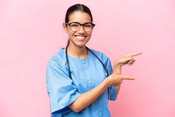 Young nurse Colombian woman isolated on pink background pointing finger to the side and presenting...