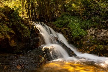 Small waterfall with long exposure in a forest on a sunny day