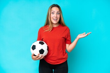 Young football player woman isolated on blue background with shocked facial expression
