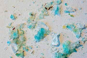 Closeup shot of the blue colored waste of a leaked battery on a white surface