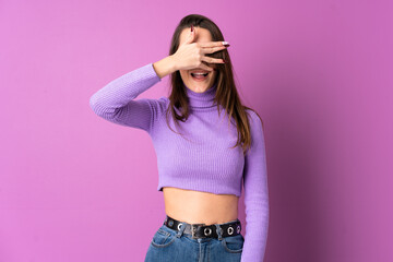 Young woman over isolated purple background covering eyes by hands and smiling