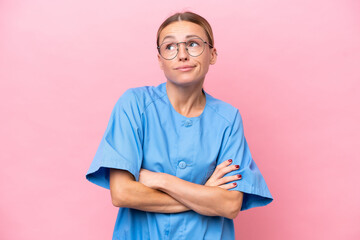 Young nurse doctor woman isolated on pink background making doubts gesture while lifting the...