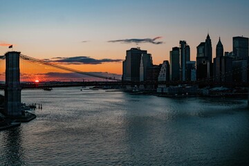 Beautiful sunset on the Brooklyn Bridge near the town, with an orange sky in the background
