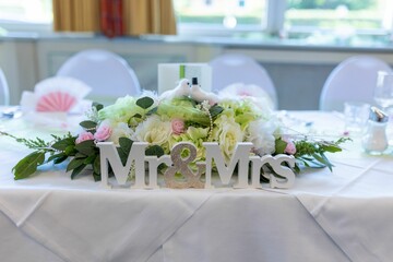 Close-up shot of a table decoration with flowers and Mr & Mrs sign