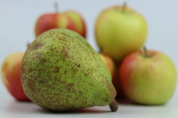 Closeup shot of a group of apples and a pear on a white background.