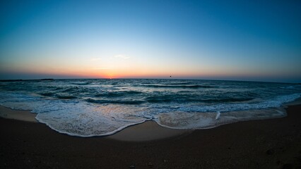 Beautiful shot of sea waves splashing onto a shore at sunset
