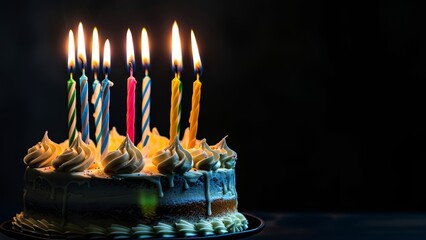 Candles burning on a festive cake on the dark background