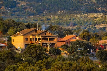 Beautiful shot of buildings on the hill, among green trees in Robledo de Chavela, in Madrid, Spain © Wirestock