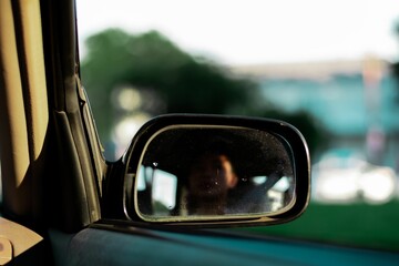 Person reflecting in car side mirror