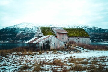 Old wooden building and rocky mountains covered with snow, Tromso, Norway
