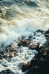 Vertical shot of stormy foamy sea waves crashing into the rocky coastline