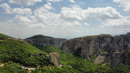 Aerial shot of the rocky mountains covered with green grass, Meteora, Greece